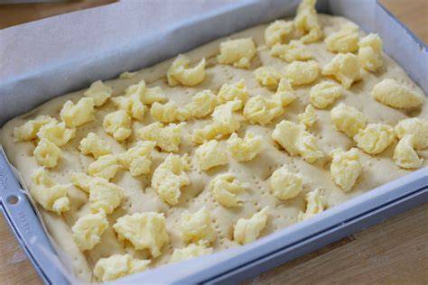 Kokosbelag wird auf den vorgebackenen Kuchen gestrichen
