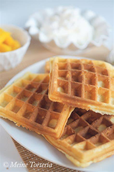 Kokoswaffeln auf einem Teller mit Mangoscheiben und Sahne