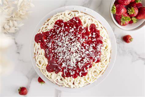 Kreatives Servieren der Spaghetti Eis Torte mit weißen Schokospänen und frischen Erdbeeren