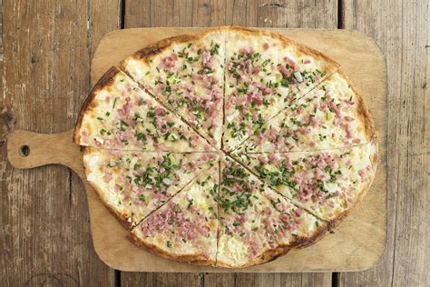Lauch-Schinken-Torte aufgeschnitten auf einem Holzbrett, Zutaten drumherum