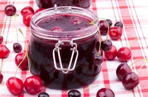 Leckere Kirschmarmelade im Glas, daneben entkernte Kirschen
