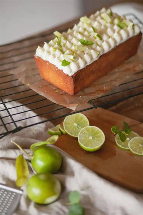 Limettenkuchen auf weißem Teller mit Limetten und Minze garniert