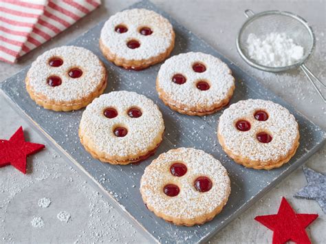 Linzer Augen mit Ribiselmarmelade und Puderzucker auf Holztisch