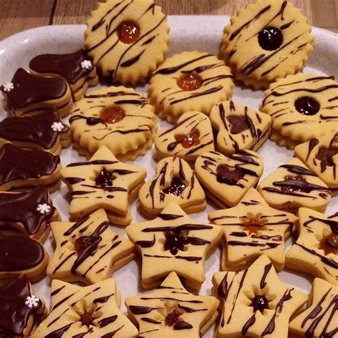 Linzer Kekse mit Nüssen, bestäubt mit Puderzucker, mit Kuvertüre und Walnuss
