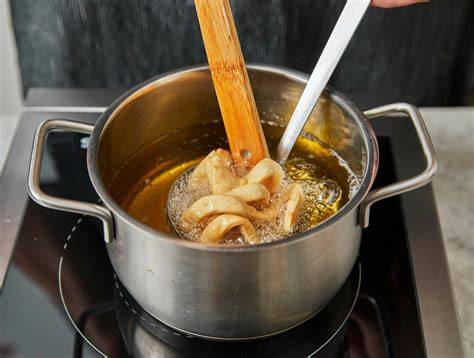 Mürbeteig-Schneeballen: gewebte Streifen in Schöpfkelle beim Frittieren