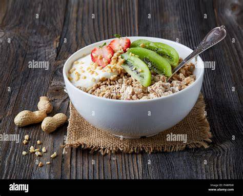 Müsli mit Früchten und Löffel auf Holztisch