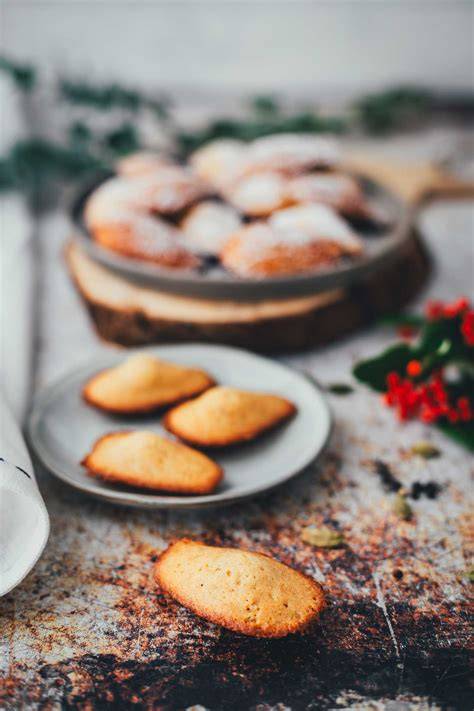 Madeleines auf einem Kuchengitter, bestäubt mit Puderzucker