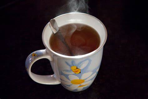 Manuka-Honig im Löffel über einer Tasse Tee