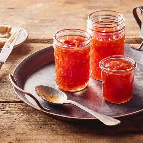 Marmeladengläser mit grüner Tomatenmarmelade auf einem Holzbrett