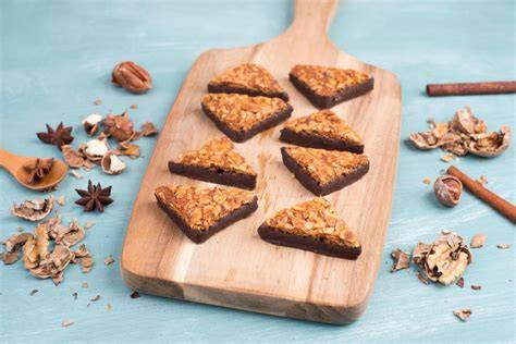 Marzipan-Nusswürfel auf Holzbrett, angeschnittene Würfel, Walnüsse und Aprikosenmarmelade