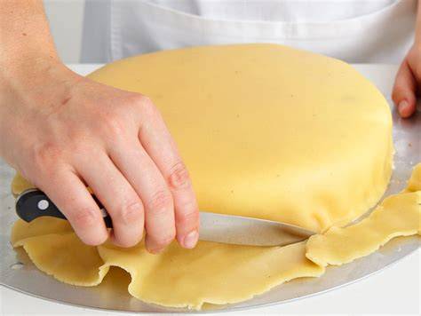 Marzipandecke auf einer Torte ausrollen und auflegen