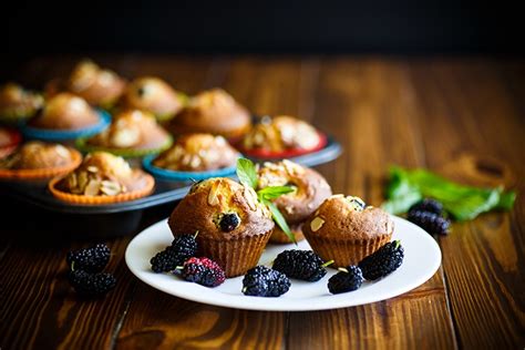 Maulbeer-Muffins mit frischen Maulbeeren und Minze angerichtet