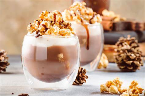 Milchkaffee mit Karamell und Popcorn auf einem Tisch, daneben kleine Desserts