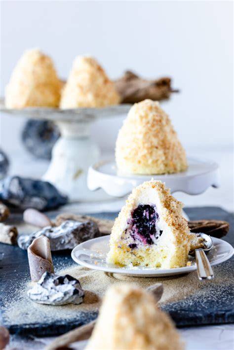 Mini-Sandburgen auf Teller dekoriert mit Brombeeren und Biskuitbröseln