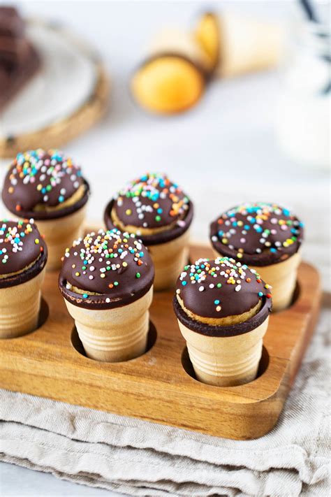 Mini-Waffelbecher-Kuchen auf einem Kuchengitter, glänzende Schokoglasur und bunte Streusel