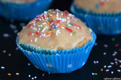 Mit Glasur bestrichene Muffins, einige mit bunten Streuseln