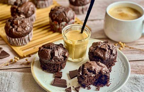 Muffins auf einem Holzbrett neben einer Tasse Kaffee