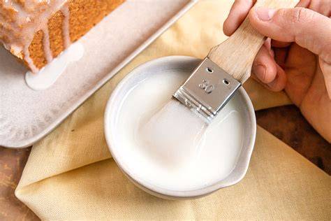 Nahaufnahme Kurkuma und Puderzucker, gelber Zuckerguss auf Muffin