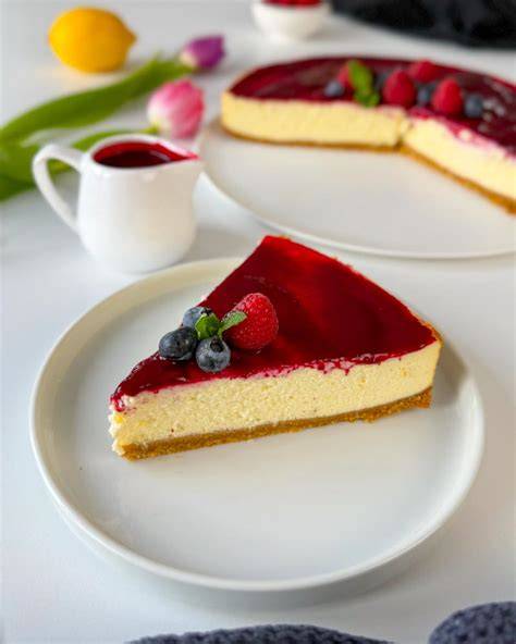 New York Cheesecake mit Himbeersoße und frischen Beeren garniert