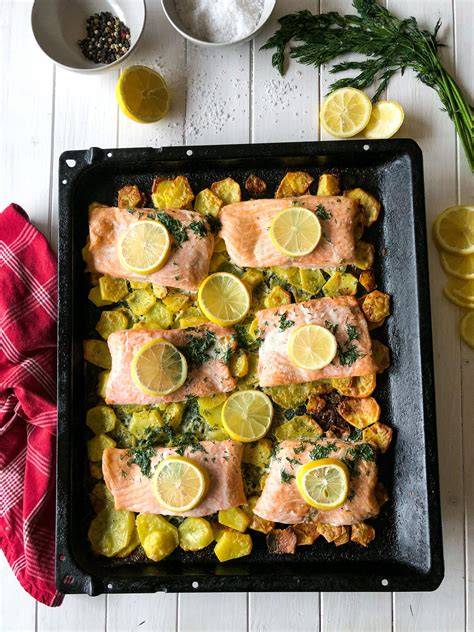 Ofenlachs mit Honig-Marinade auf Zitronenscheiben, daneben Kartoffeln und Lauchzwiebeln