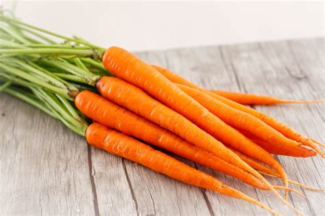 Orangen und geraspelte Karotten auf Holztisch