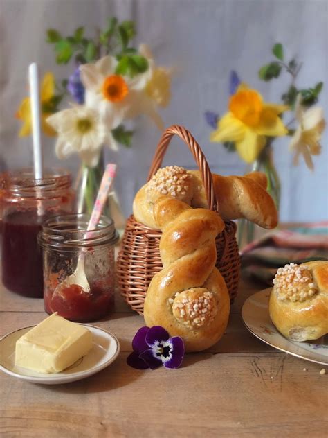 Osterbrunch-Tisch mit Hefehasen, Marmelade, frischen Blumen und Kinderhänden
