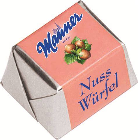 Packung Manner Nuss Würfel neben einer Tasse Kaffee; Nahaufnahme eines aufgebrochenen Würfels mit Haselnusscreme