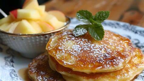 Pancakes mit Apfelmus auf dem Teller angerichtet mit Beeren