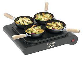 Party Wokset auf dem Esstisch mit vier Wokpfännchen und Zutaten