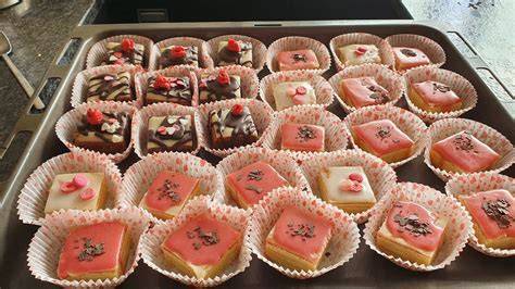 Petits Fours auf einem Kuchengitter dekoriert mit pastellfarbener Glasur und essbaren Blüten