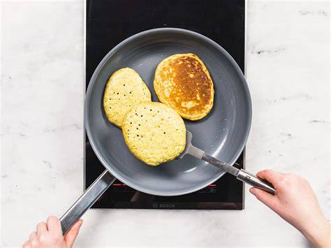 Pfanne mit Pancakes, auf denen sich Bläschen bilden - Pfannkuchen vor dem Wenden