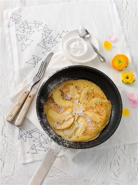 Pfanne mit Pfannkuchenteig, darauf Apfelspalten und Marzipanwürfel