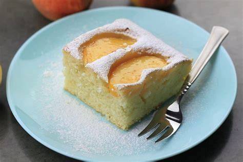 Pfirsich-Blechkuchen auf rustikalem Brett, Zutaten und Thermomix im Hintergrund