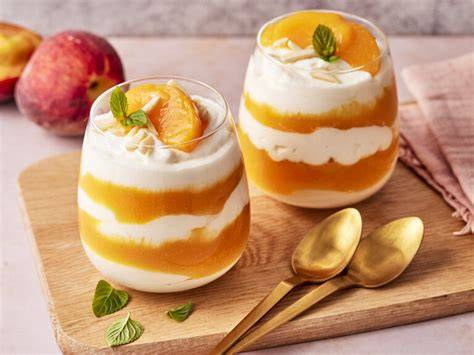 Pfirsich-Quark-Dessert dekoriert mit Minze und Mandeln