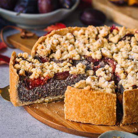 Pflaumen-Nuss-Torte auf rustikalem Holzbrett mit Zwetschgen und Haselnüssen