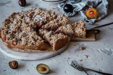 Pflaumenkuchen mit Streuseln auf rustikalem Brett, Zwetschgen, Thermomix im Hintergrund
