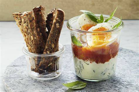Pikante Marmeladen im Glas mit kleinen Schälchen, angerichtet neben Käsewürfeln