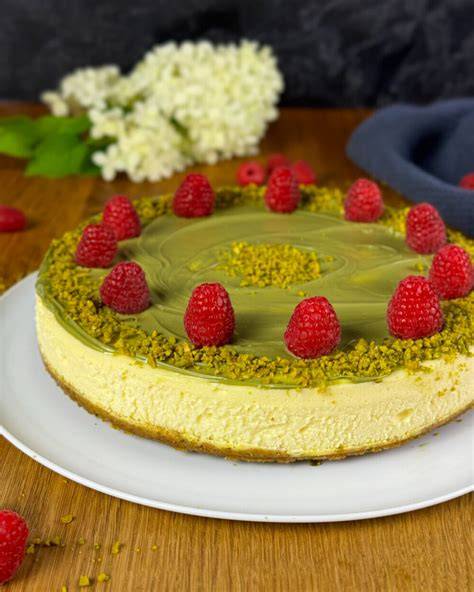Pistazien Cheesecake auf einer Kuchenplatte mit frischen Beeren und Pistazien-Topping
