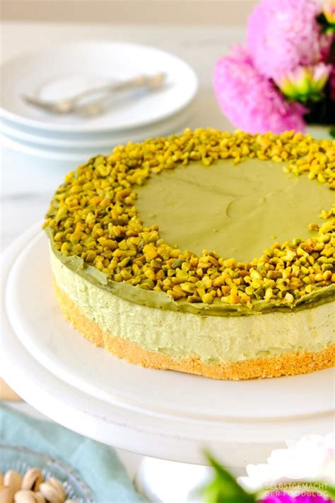 Pistazien-Cheesecake aufgeschnitten mit grünem Spiegel und gehackten Pistazien