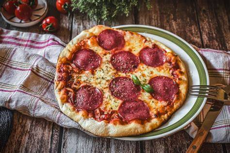 Pizza mit Salami, Knoblauchöl, Honig und Salbei frisch aus dem Pizzaofen