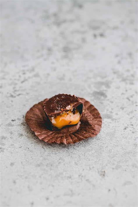 Pralinen und Schokoladentafel mit salzigem Karamell auf rustikalem Holztisch