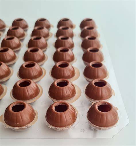 Pralinen-Hohlkugeln und Silikonformen mit geschmolzener Schokolade