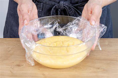 Pudding in einer Glasschüssel mit Frischhaltefolie, daneben eine Gefriertruhe