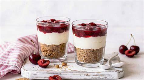 Pudding mit Keksbröseln und angedickten Kirschen in einem Glas serviert