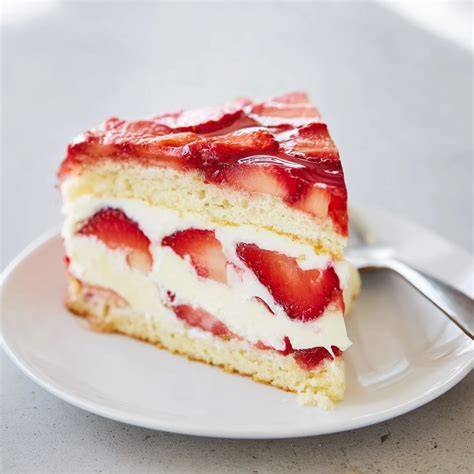 Querschnitt durch eine Erdbeer-Biskuit-Torte: luftiger Boden, cremige Schichten, frische Früchte