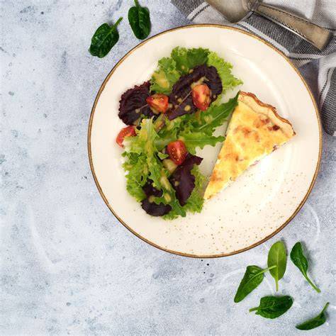Quiche Lorraine serviert mit grünem Salat und Wein