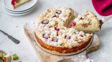 Rhabarber Quark Kuchen angeschnitten auf Tortenplatte mit Streuseln und Puderzucker