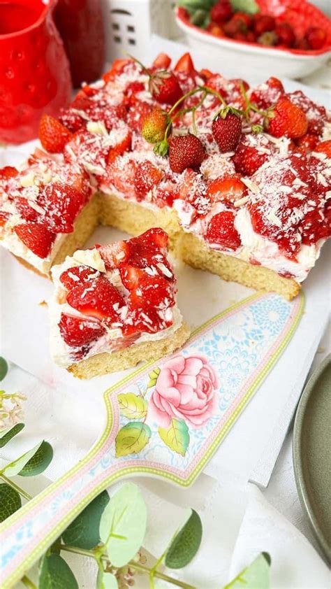 Rhabarber-Biskuit-Torte im Anschnitt, frische Erdbeeren und Minze zur Dekoration