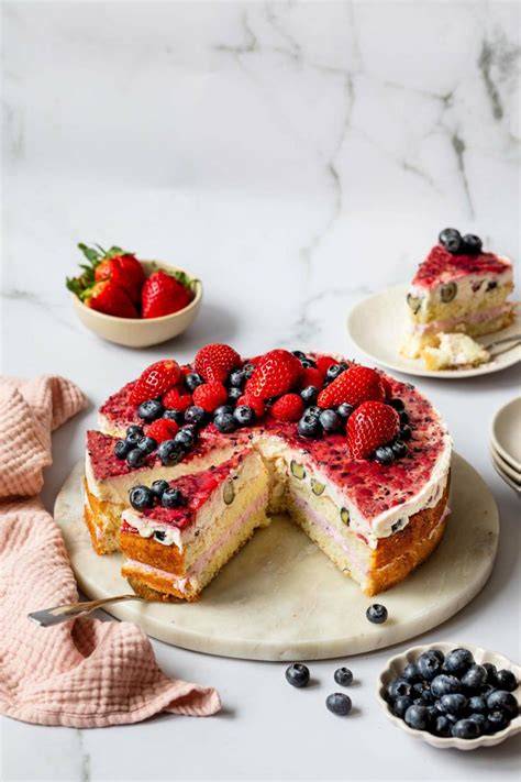 Ricotta-Torte auf Tortenplatte mit sommerlichen Beeren und Minze