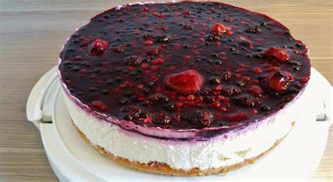 Rote Grütze Torte auf weißem Tortenteller, mit frischen Beeren garniert